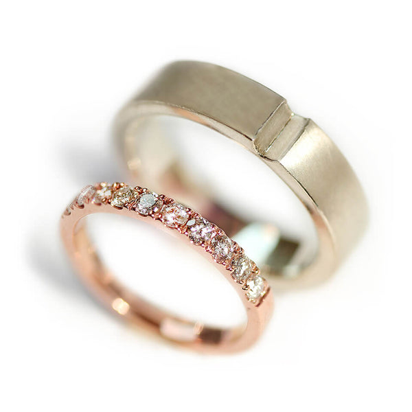 Detail of the narrow rose gold diamond band beside the wider matte white gold ring