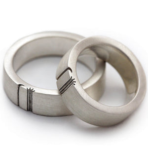Detail of the engraved sun rays and crescent moon extending across both wide wedding bands