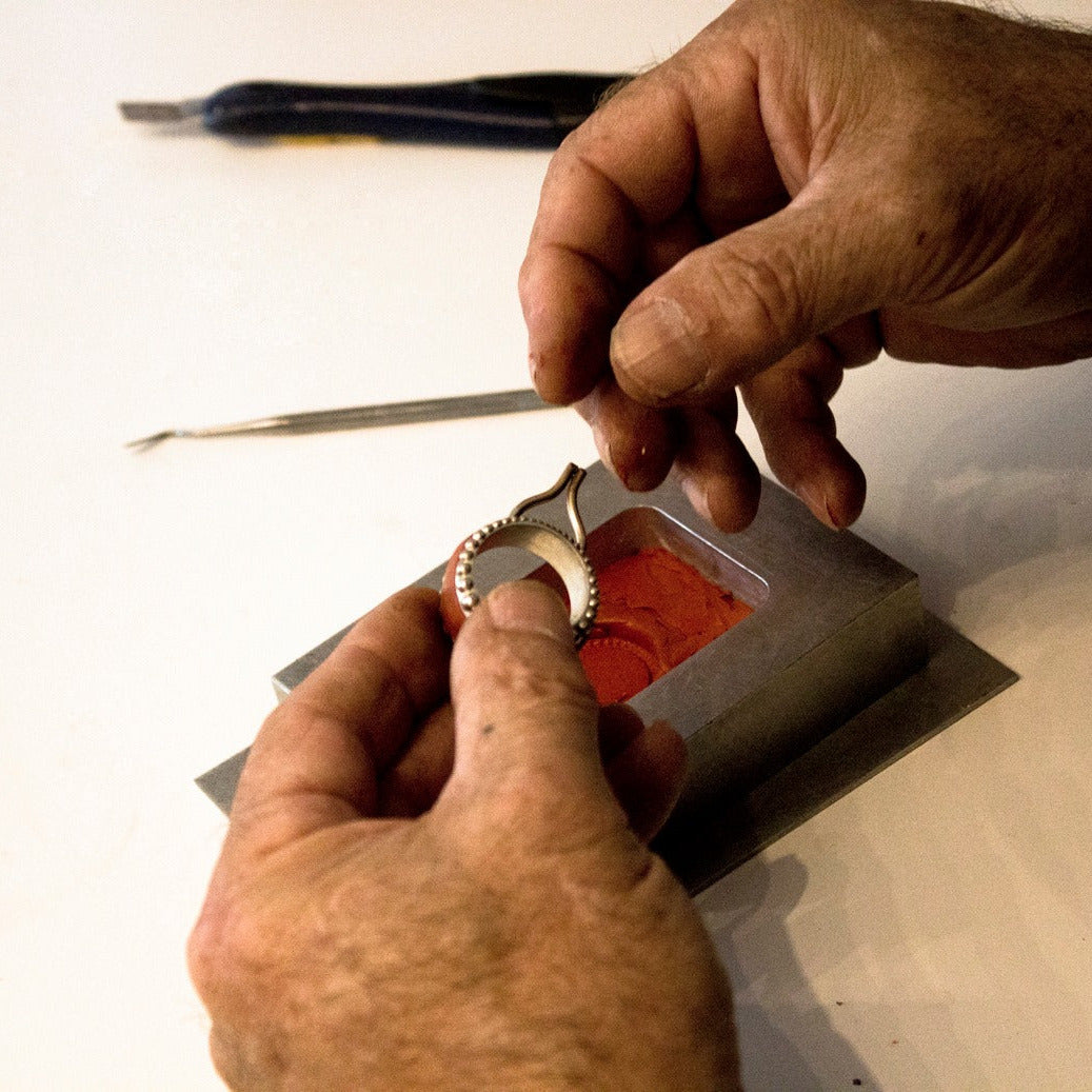 Close-up of hands working with a small tool on a white surface
