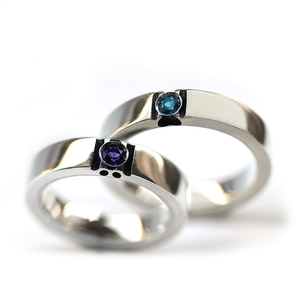 Matching white gold couple rings with amethyst and blue topaz birthstones showing hidden paw print design revealed when rings align.
