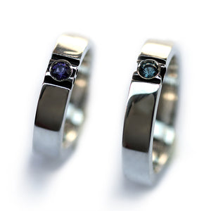 Two polished white gold paw print rings standing upright showing gemstone centers and clean modern couple wedding band design.