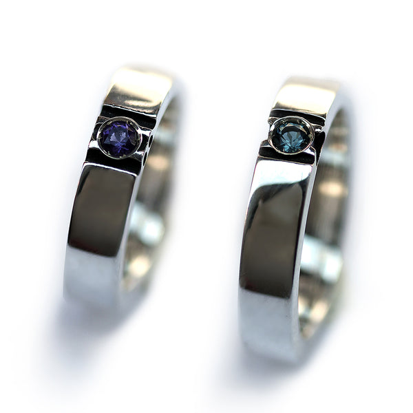 Two polished white gold paw print rings standing upright showing gemstone centers and clean modern couple wedding band design.