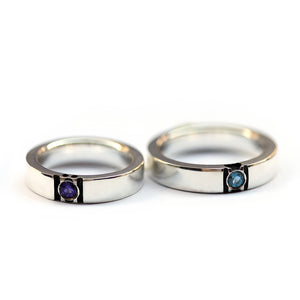 Pair of paw print wedding rings lying flat showing gemstone placement and subtle hidden paw negative space couple ring structure.