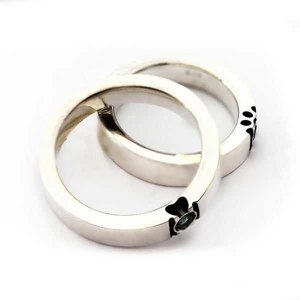 Overlapping white gold birthstone rings revealing side paw silhouette details and symbolic pet lover matching rings design.