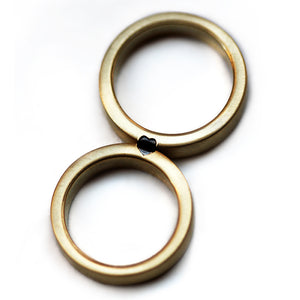 Matching couple wedding rings with black diamond heart detail, handcrafted 18K gold bands with brushed matte finish, personalized wedding jewelry