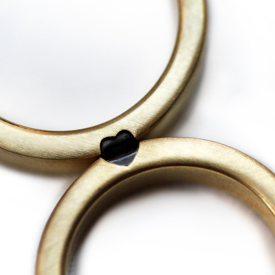 Personalized wedding ring set forming hidden heart when united, black diamond accent bands handmade with professional engraving options, artisan wedding jewelry Barcelona