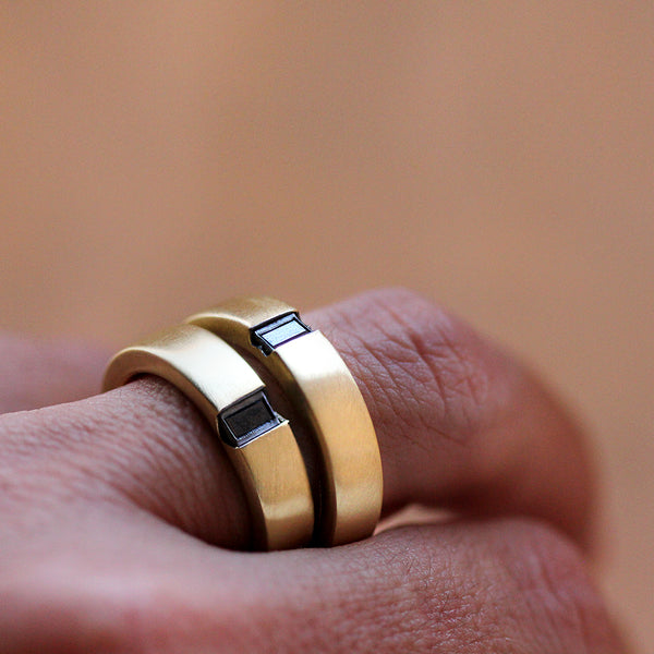 His and hers wedding bands with black baguette diamonds, 18K yellow gold matching rings with matte finish worn on hand, custom engagement rings