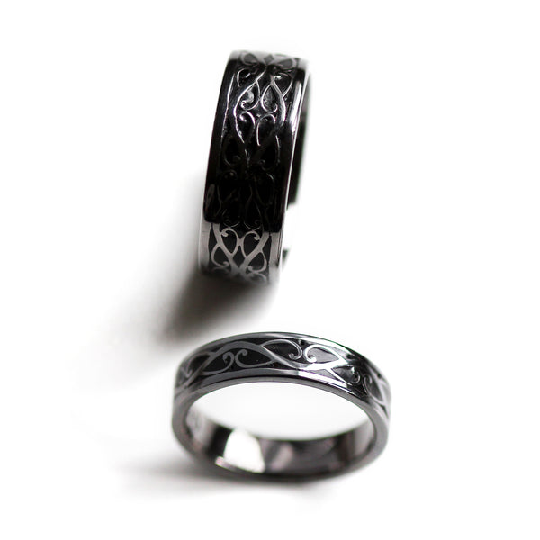 Lifestyle view of matching black rhodium Celtic wedding rings worn on hands featuring braided silver motif and black hot enamel inlay