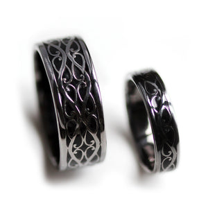 Side angle of black rhodium Celtic braided his and hers wedding bands with polished silver detailing and black hot enamel background