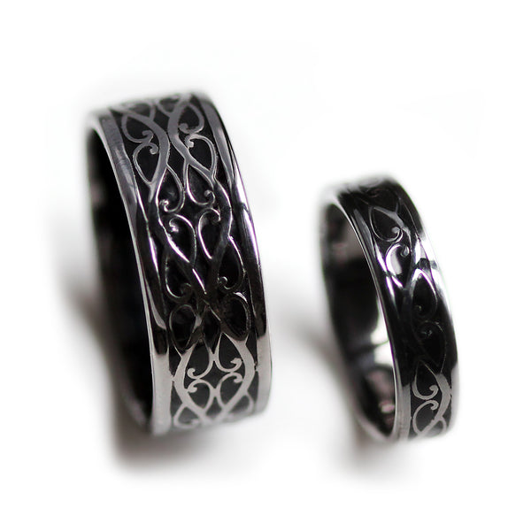 Side angle of black rhodium Celtic braided his and hers wedding bands with polished silver detailing and black hot enamel background