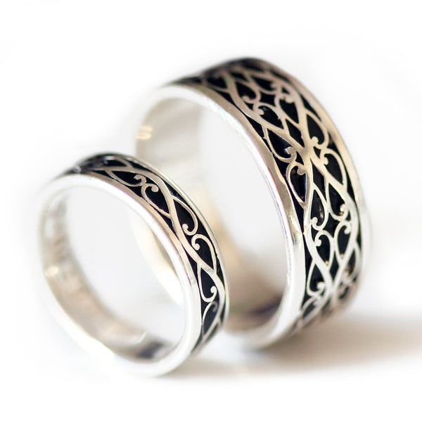 Matching Celtic braided his and hers wedding rings in sterling silver featuring black hot enamel inlay and polished braid pattern