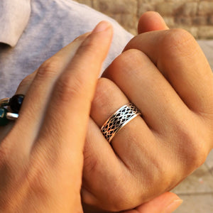 Lifestyle close up of sterling silver Celtic wedding ring with braided pattern and black hot enamel detailing