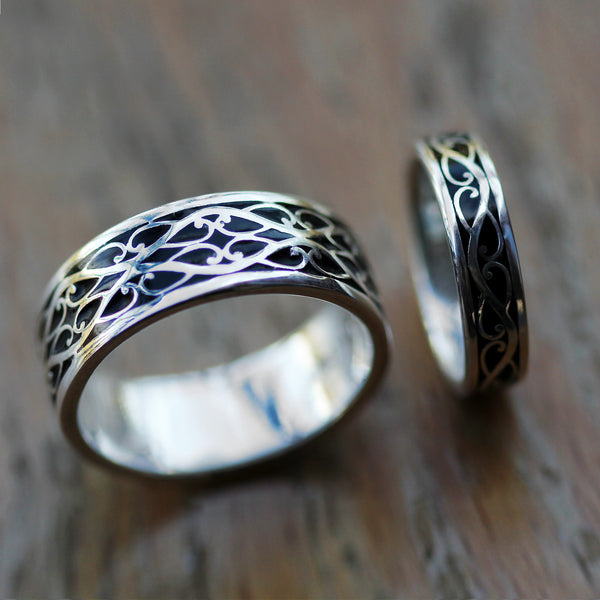 Rustic display of Celtic braided wedding ring set in sterling silver with black hot enamel inlay and polished finish
