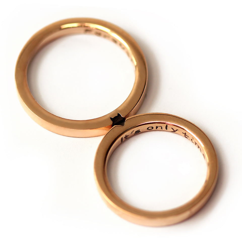 Two 18K rose gold couple rings placed side by side showing the engraved fox silhouette across the outer surface of both matching bands.