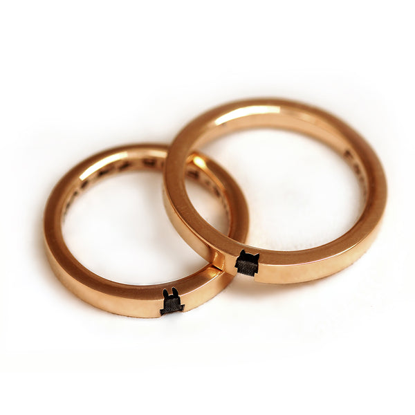 Top view of the matching rose gold rings showing the upper portions of both the fox and bunny silhouettes engraved into the bands.