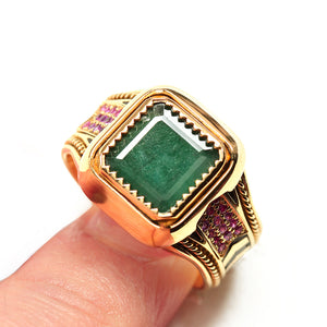 Handcrafted yellow gold statement ring featuring square emerald center stone, ruby accent side stones, filigree engraving and black hot enamel chevron band