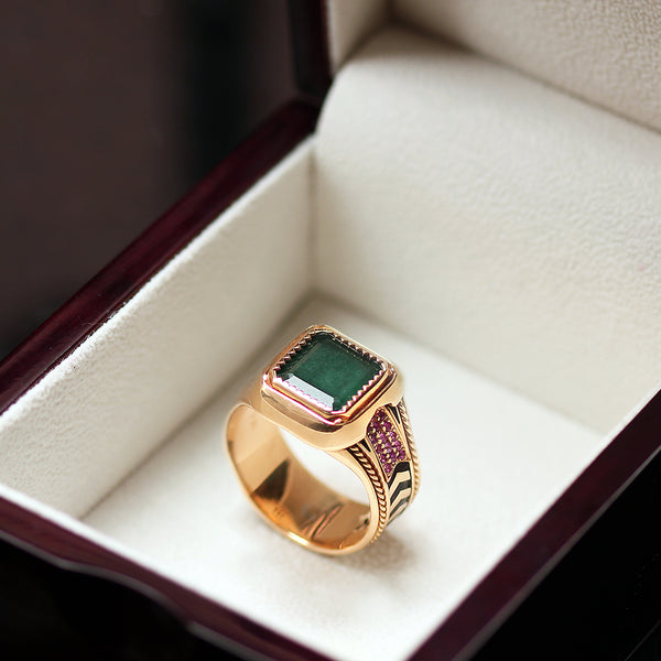 Emerald and ruby statement ring displayed in jewelry box showing vintage inspired filigree detailing, geometric chevron design and black hot enamel inlay band