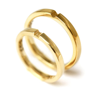 Polished yellow gold matching couple rings with hidden heart connection detail, luxury minimalist wedding bands