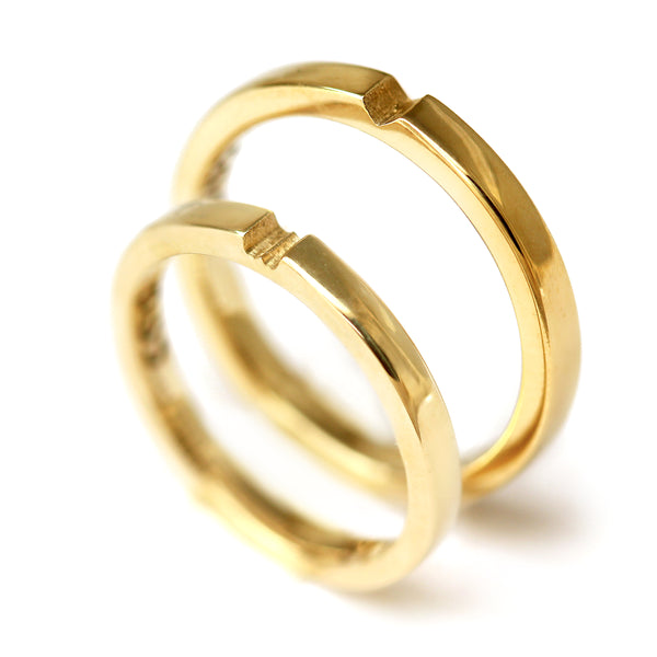 Polished yellow gold matching couple rings with hidden heart connection detail, luxury minimalist wedding bands