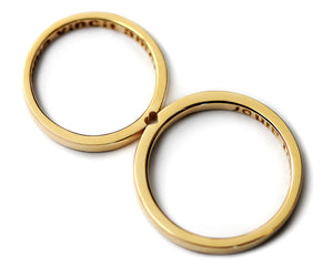 Yellow gold couple rings forming hidden heart connection, elegant modern wedding band set