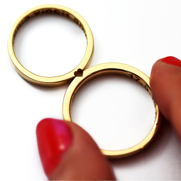 Hand holding yellow gold hidden heart couple rings, symbolic matching relationship rings