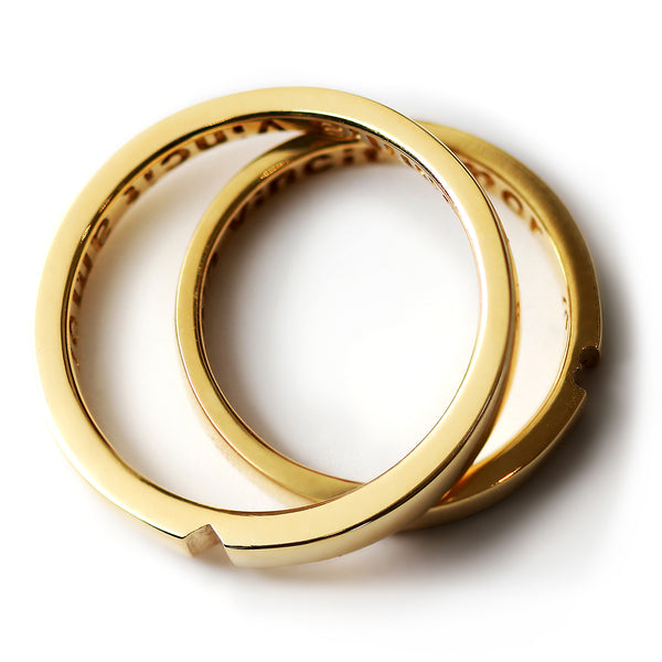 Yellow gold matching wedding rings interlocked revealing hidden heart symbol, luxury minimalist couple jewelry