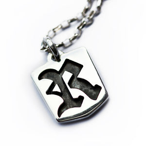 Sterling silver gothic letter pendant necklace featuring raised tag shape with Old English initial cutout and contrast background