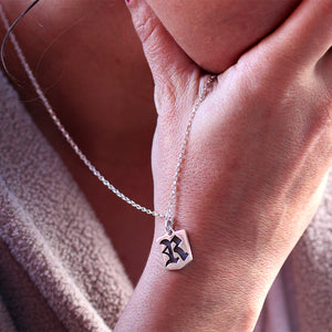 Personalized gothic initial pendant worn on hand in sterling silver necklace with Old English letter design and polished tag charm