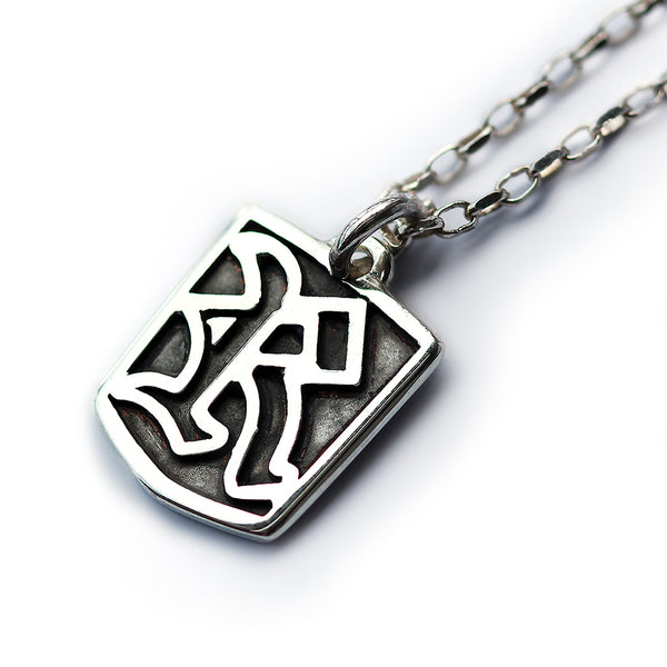 Silver ggothic initial letter tag pendant with a unique design on a white background