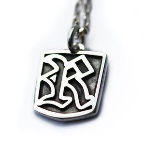 Silver gothic letter engraved pendant with a unique design on a white background