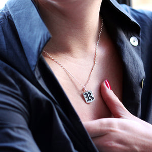 Gothic initial tag necklace worn on neck featuring sterling silver personalized Old English letter pendant with minimalist chain