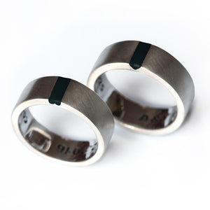 Pair of minimalist 18K white gold rings featuring a statement black enamel stripe, perfect for couples seeking "different but not weird" promise rings.