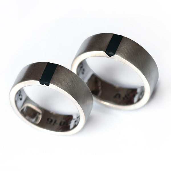 Pair of minimalist 18K white gold rings featuring a statement black enamel stripe, perfect for couples seeking "different but not weird" promise rings.