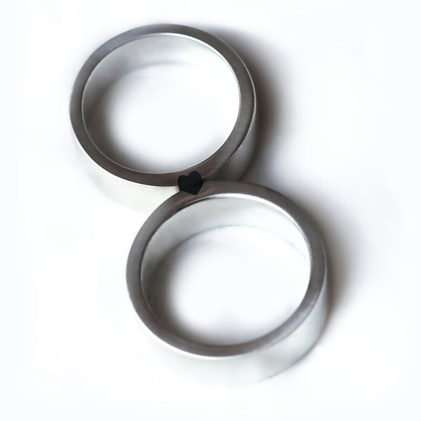 Top-down view of two rings forming a complete black enamel heart, representing a powerful and transformative bond between a couple.  