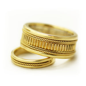 Vintage style yellow gold wedding bands featuring detailed side filigree engraving, textured fluted center and purple sapphire gemstone accent