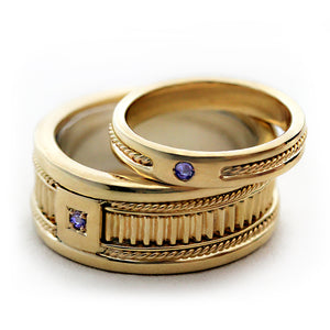 Elegant his and hers wedding ring set in yellow gold with handcrafted filigree engraving, fluted texture center band and purple sapphire gemstone detail