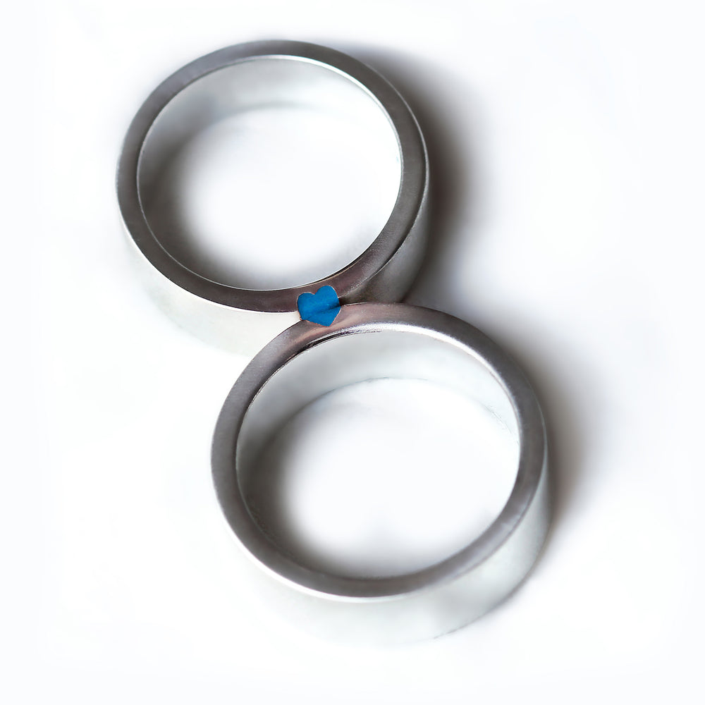 Matching couple wedding bands in silver or white gold featuring light blue enamel accent and concealed heart connection design