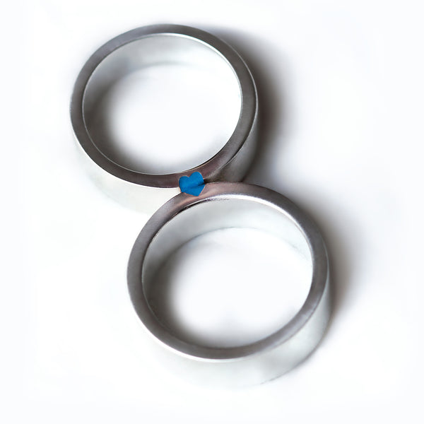 Matching wedding bands in brushed silver or white gold with light blue enamel heart revealed when rings connect.