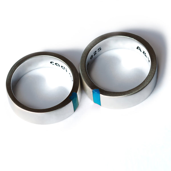 His and hers matching rings with light blue enamel inlay forming hidden heart detail in modern wedding bands design.