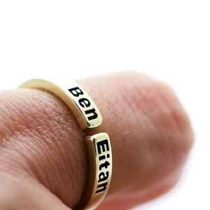 Personalized mother ring in 18K solid yellow gold open band design with engraved children’s names featuring blackened lettering on gold background, worn on hand