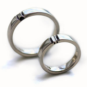 White gold his and hers rings displayed at an angle, showing the raised connection points and smooth comfort fit interior designed to form a hidden paw print when aligned.