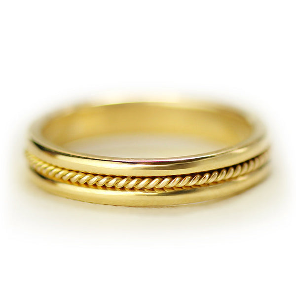 Close up of thin 18k gold sapphire wedding band featuring bezel set purple sapphire and decorative rope filigree pattern