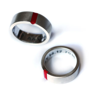 Close-up of his and hers wedding rings in white gold, highlighting the red enamel notched edges that subtly form a heart when aligned.
