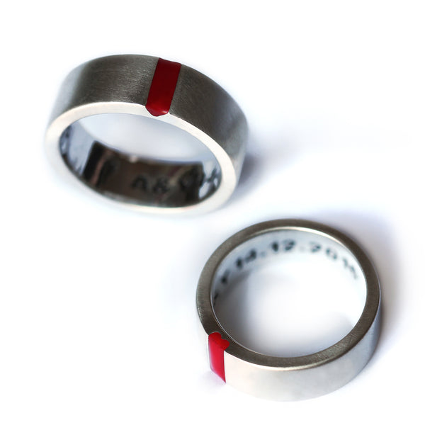 Close-up of his and hers wedding rings in white gold, highlighting the red enamel notched edges that subtly form a heart when aligned.