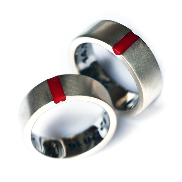 Matching 18K gold promise rings for couples with a modern minimalist design, featuring a statement red enamel "hidden heart" symbol of unity.