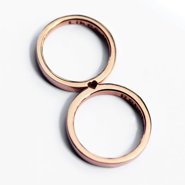 Rose gold hidden heart couple rings aligned to reveal small heart cutout, minimalist matching wedding or promise rings.