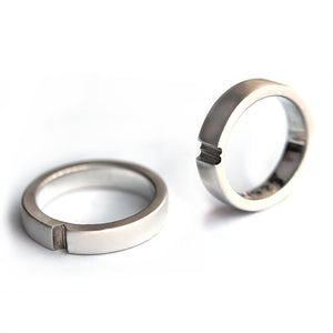 Two silver hidden heart rings separated showing interlocking notch design, contemporary his and hers wedding bands
