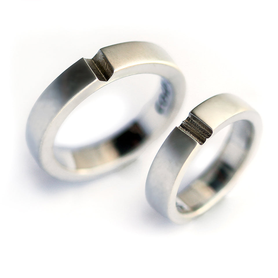Silver hidden heart couple rings aligned together revealing subtle heart cut design, minimalist matching wedding bands