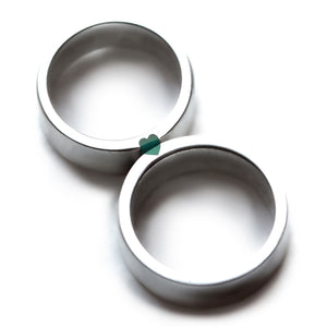Matching silver couple wedding bands with turquoise enamel stripe forming hidden heart connection.