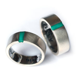 Luxury matching couple rings with turquoise enamel accent, silver wedding bands forming hidden heart symbol together.